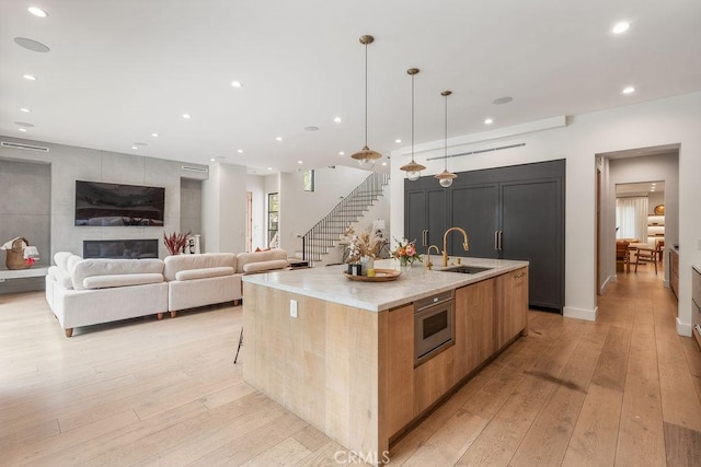 10 Seabluff, Newport Beach, CA 92660 - kitchen featuring a sink, modern cabinets, a large island, light wood-type flooring, and light stone countertops