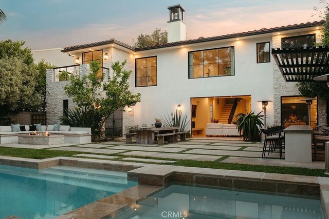10 Seabluff, Newport Beach, CA 92660 - back of house at dusk with a balcony, a patio area, stone siding, and a tiled roof
