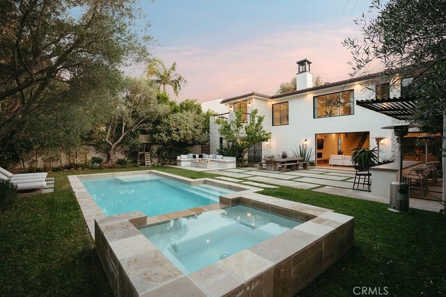 10 Seabluff, Newport Beach, CA 92660 - back of house at dusk featuring a chimney, a patio area, stucco siding, a pool with connected hot tub, and an outdoor bar