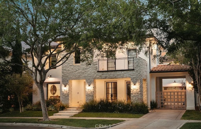 10 Seabluff, Newport Beach, CA 92660 - view of front facade with a balcony, stone siding, a garage, driveway, and stucco siding