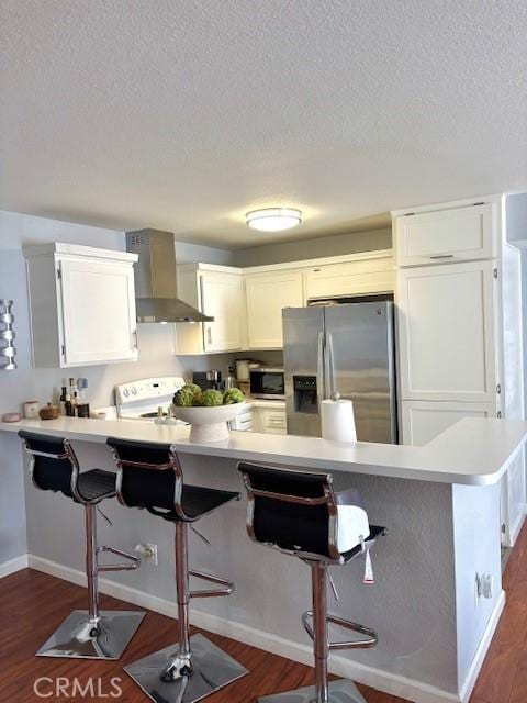 15000 Downey Ave Unit 273, Paramount, CA 90723 - kitchen with wall chimney exhaust hood, appliances with stainless steel finishes, a kitchen bar, a peninsula, and a textured ceiling
