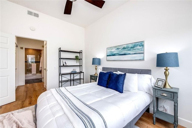 bedroom with wood finished floors, connected bathroom, and a ceiling fan