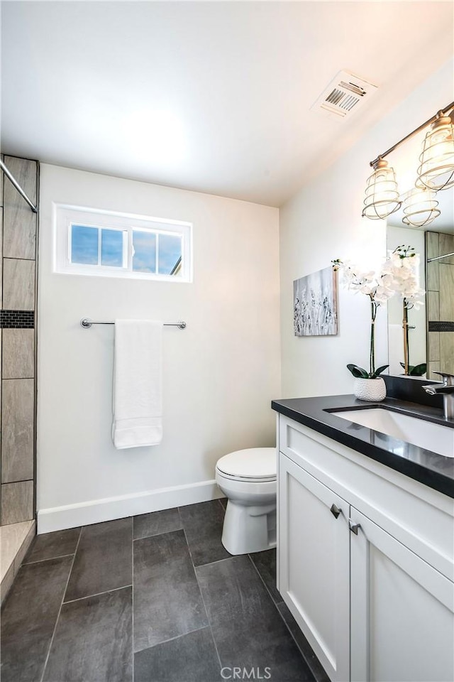 full bathroom with toilet, tiled shower, vanity, tile patterned floors, and baseboards