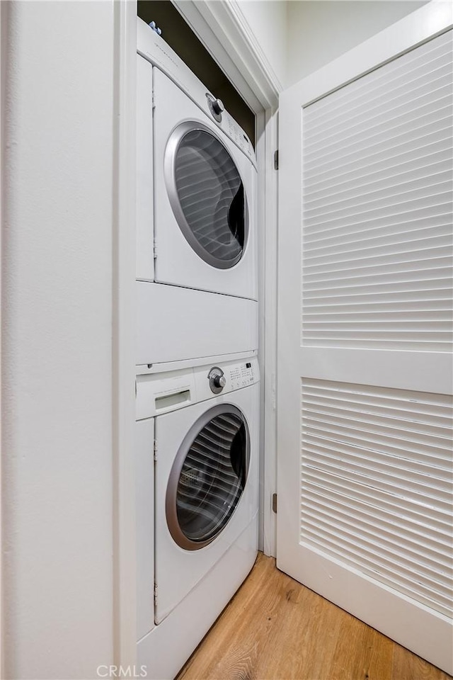 laundry area with stacked washer / dryer and light wood finished floors