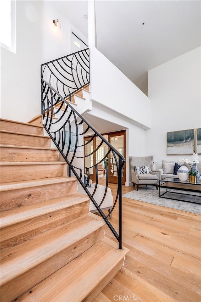 stairs featuring wood finished floors and a towering ceiling