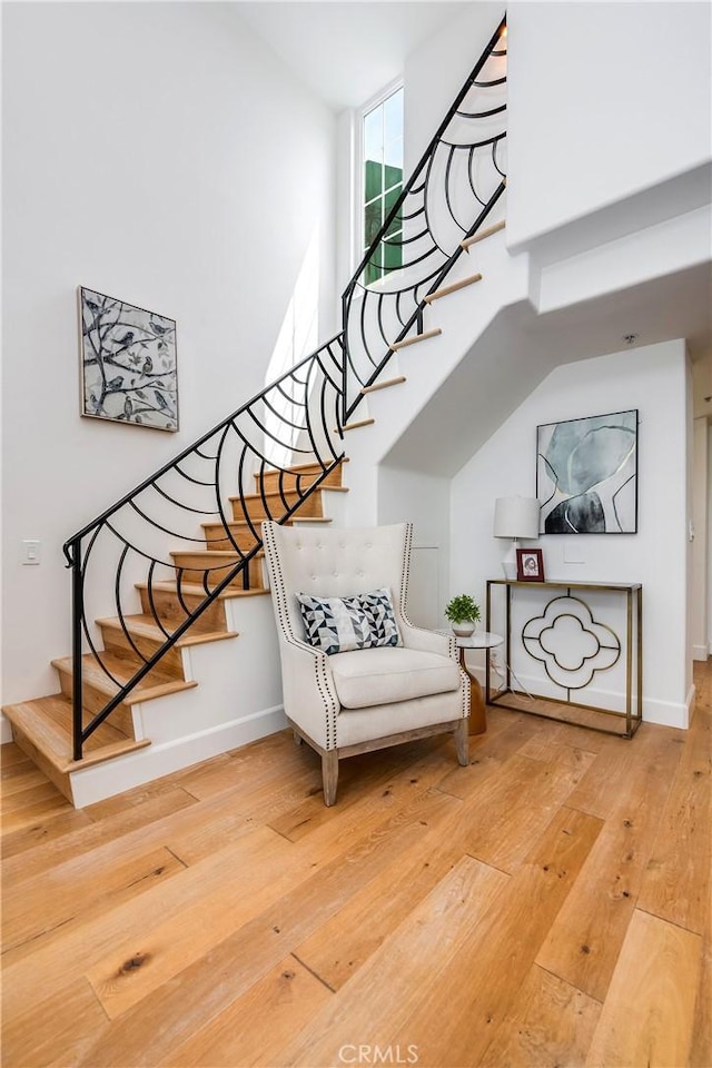 stairs featuring wood-type flooring, baseboards, and a high ceiling