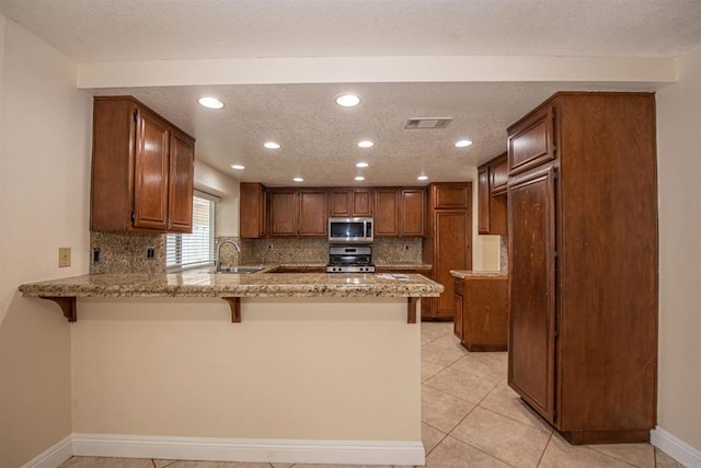 28679 Corte Capri, Menifee, CA 92584 - kitchen featuring stainless steel appliances, a peninsula, a sink, light stone countertops, and decorative backsplash