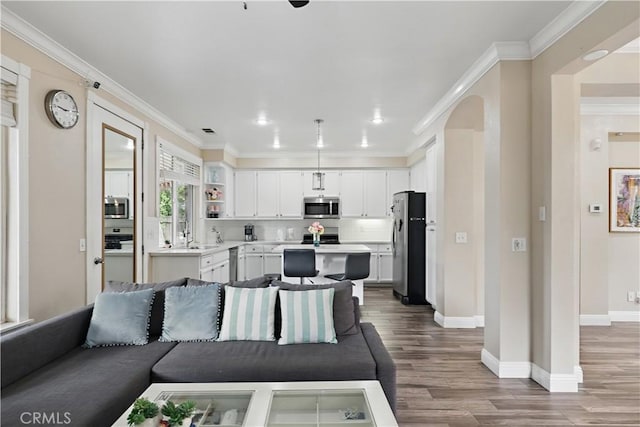 1958 Fall Brook Ct, Merced, CA 95340 - living area featuring wood finished floors, baseboards, arched walkways, ornamental molding, and recessed lighting