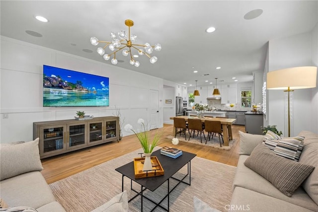 living area featuring recessed lighting, light wood-style floors, and a chandelier
