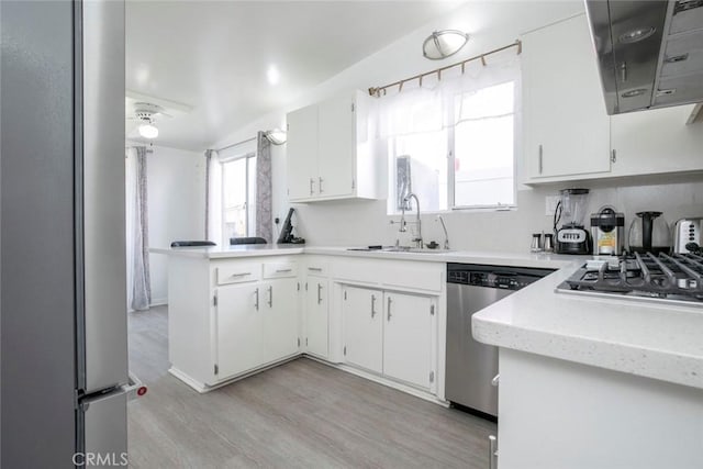 7700 Goodland Ave, North Hollywood, CA 91605 - kitchen featuring appliances with stainless steel finishes, a sink, white cabinets, a peninsula, and light wood finished floors