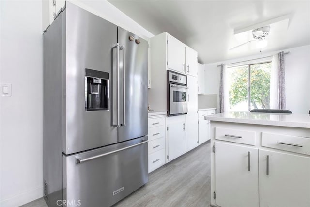7700 Goodland Ave, North Hollywood, CA 91605 - kitchen with appliances with stainless steel finishes, light countertops, white cabinets, light wood-type flooring, and a ceiling fan