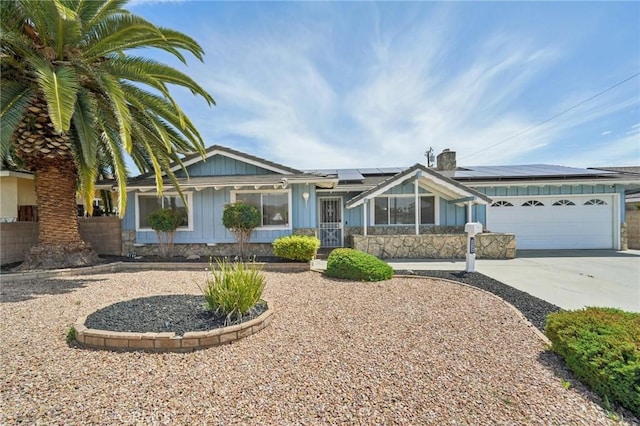 40389 Melrose Ave, Hemet, CA 92544 - ranch-style house with board and batten siding, a garage, roof mounted solar panels, concrete driveway, and a chimney