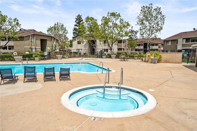 community pool featuring a community hot tub, fence, a residential view, and a patio
