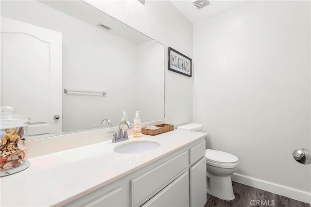 bathroom featuring wood finished floors, vanity, toilet, and baseboards