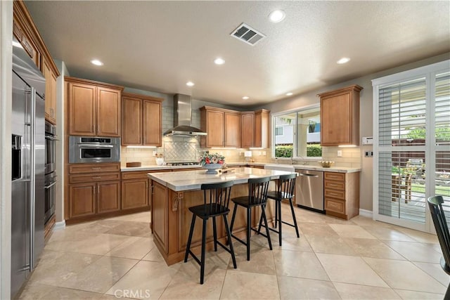 45133 Fieldbrook Ct, Temecula, CA 92592 - kitchen with wall chimney exhaust hood, appliances with stainless steel finishes, brown cabinets, light countertops, and recessed lighting