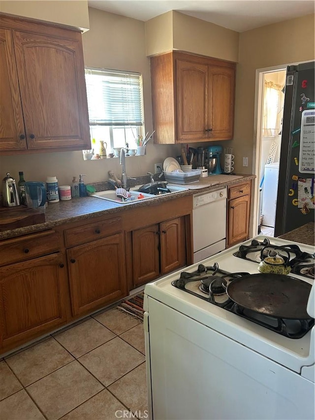 8900 Geyser Ave, Northridge, CA 91324 - kitchen with white appliances, brown cabinetry, light tile patterned floors, a sink, and washer / clothes dryer