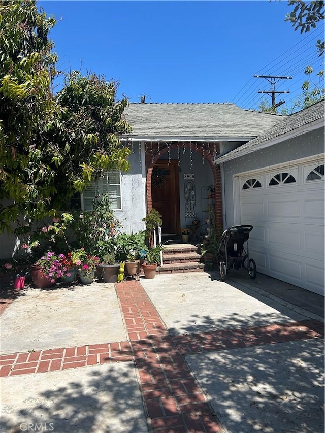 8900 Geyser Ave, Northridge, CA 91324 - property entrance with a garage, a shingled roof, and concrete driveway