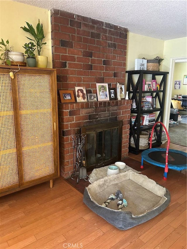 8900 Geyser Ave, Northridge, CA 91324 - living room featuring wood-type flooring, a textured ceiling, and a brick fireplace