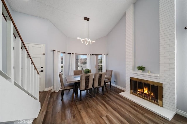 11396 Burl Dr, Fontana, CA 92337 - dining space featuring a chandelier, baseboards, wood finished floors, stairs, and a brick fireplace