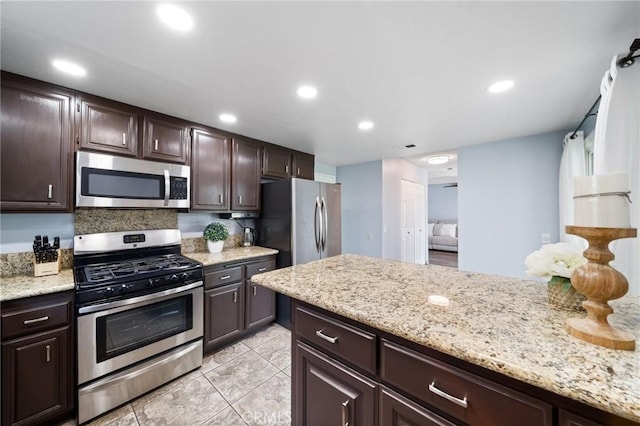 11396 Burl Dr, Fontana, CA 92337 - kitchen featuring appliances with stainless steel finishes, dark brown cabinets, light tile patterned floors, recessed lighting, and light stone counters