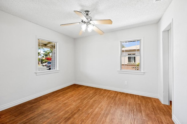 spare room with wood finished floors, baseboards, a textured ceiling, and ceiling fan