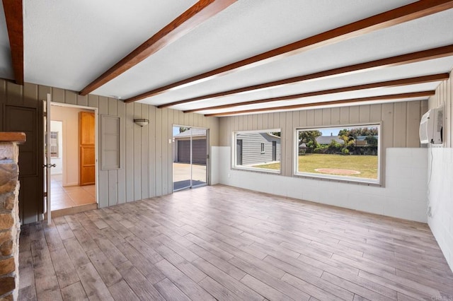 unfurnished living room with wood finished floors and beamed ceiling