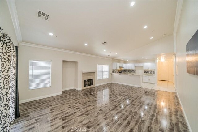 7404 Marshall Ct, Highland, CA 92346 - unfurnished living room with ornamental molding, light wood-style flooring, recessed lighting, lofted ceiling, and a fireplace