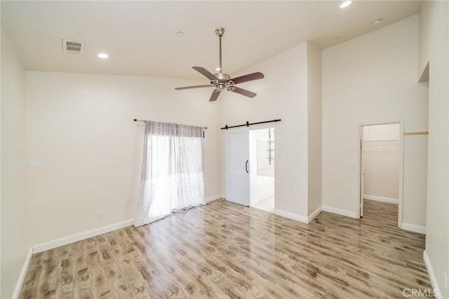 7404 Marshall Ct, Highland, CA 92346 - spare room featuring light wood-style floors, ceiling fan, a barn door, high vaulted ceiling, and recessed lighting