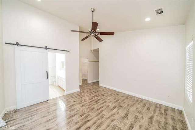 7404 Marshall Ct, Highland, CA 92346 - unfurnished bedroom with light wood-style flooring, a barn door, baseboards, recessed lighting, and ensuite bathroom