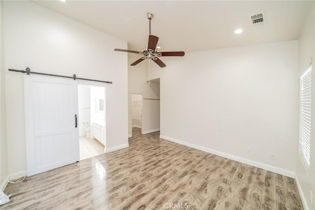 7404 Marshall Ct, Highland, CA 92346 - unfurnished bedroom with light wood-style floors, a barn door, recessed lighting, ensuite bath, and a spacious closet