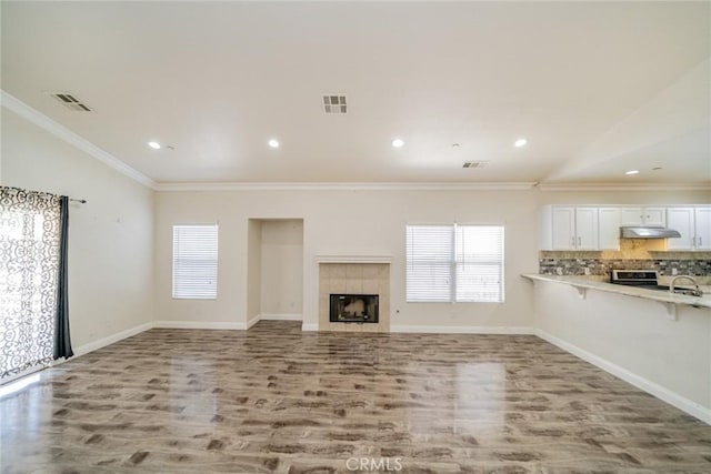 7404 Marshall Ct, Highland, CA 92346 - unfurnished living room with vaulted ceiling, wood finished floors, plenty of natural light, crown molding, and a tile fireplace