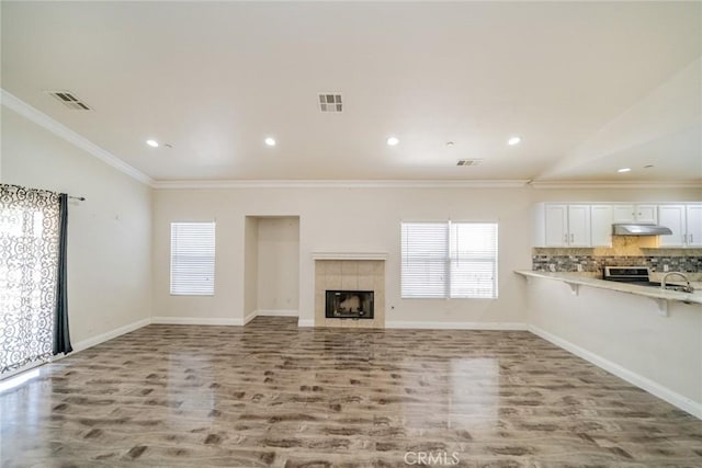 7404 Marshall Ct, Highland, CA 92346 - unfurnished living room featuring vaulted ceiling, wood finished floors, plenty of natural light, crown molding, and a fireplace
