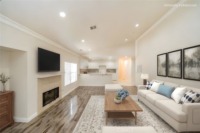 7404 Marshall Ct, Highland, CA 92346 - living room featuring crown molding, light wood-style flooring, a tiled fireplace, baseboards, and recessed lighting