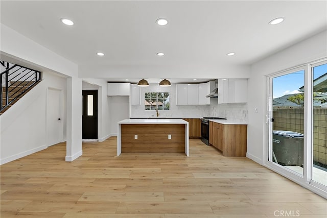 19617 Enslow Dr, Carson, CA 90746 - kitchen with wall chimney range hood, range with gas cooktop, a sink, white cabinetry, and light wood finished floors