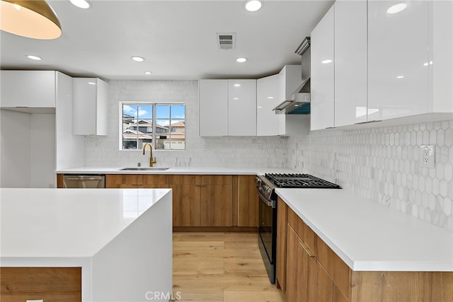 19617 Enslow Dr, Carson, CA 90746 - kitchen with range with gas cooktop, modern cabinets, a sink, light wood-type flooring, and white cabinetry