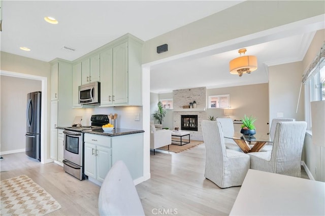 524 N Paulina Ave, Redondo Beach, CA 90277 - kitchen with appliances with stainless steel finishes, light wood finished floors, dark countertops, a large fireplace, and ornamental molding