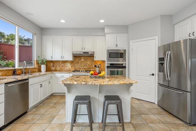 6628 Sitio Sago, Carlsbad, CA 92011 - kitchen with stainless steel appliances, a sink, white cabinets, under cabinet range hood, and light stone counters