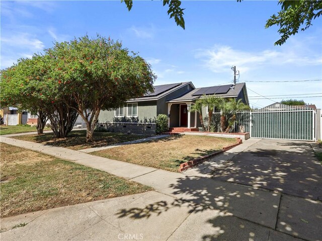 8110 Lesner Ave, Lake Balboa, CA 91406 - view of front of house with driveway, a gate, roof mounted solar panels, a front lawn, and stucco siding