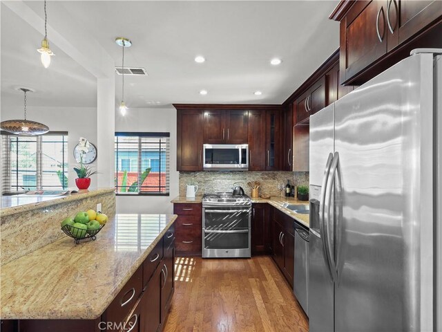 8110 Lesner Ave, Lake Balboa, CA 91406 - kitchen with appliances with stainless steel finishes, wood finished floors, decorative backsplash, light stone counters, and pendant lighting