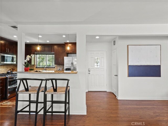 8110 Lesner Ave, Lake Balboa, CA 91406 - kitchen with appliances with stainless steel finishes, a kitchen breakfast bar, dark brown cabinetry, backsplash, and recessed lighting