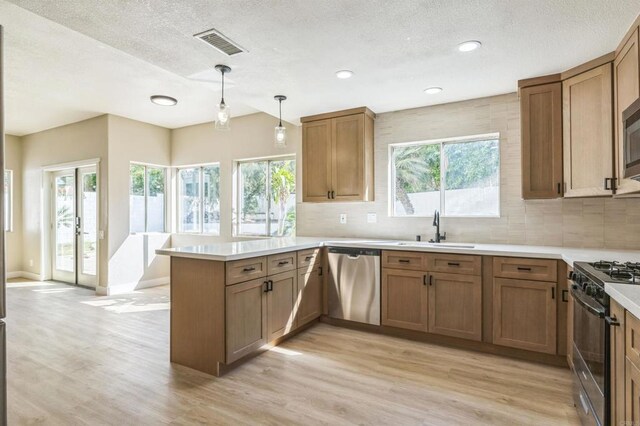 40550 Ventana Ct, Palm Desert, CA 92260 - kitchen featuring appliances with stainless steel finishes, a peninsula, a sink, light wood-style flooring, and tasteful backsplash