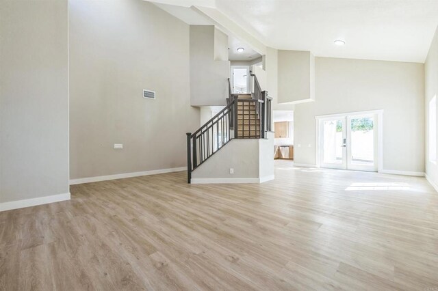 40550 Ventana Ct, Palm Desert, CA 92260 - unfurnished living room featuring stairs, light wood-style flooring, french doors, baseboards, and a towering ceiling