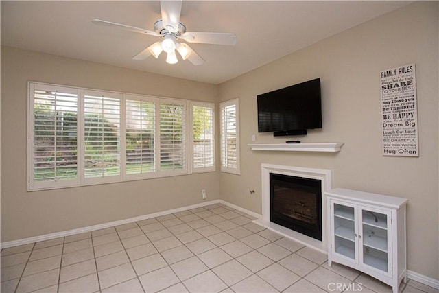 unfurnished living room featuring ceiling fan, a fireplace, baseboards, and light tile patterned floors