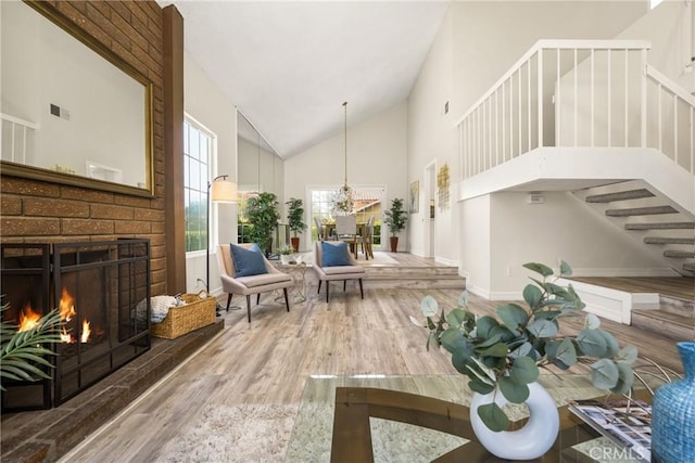 15541 Olive Branch Dr, La Mirada, CA 90638 - living area with high vaulted ceiling, stairs, wood finished floors, a brick fireplace, and a chandelier