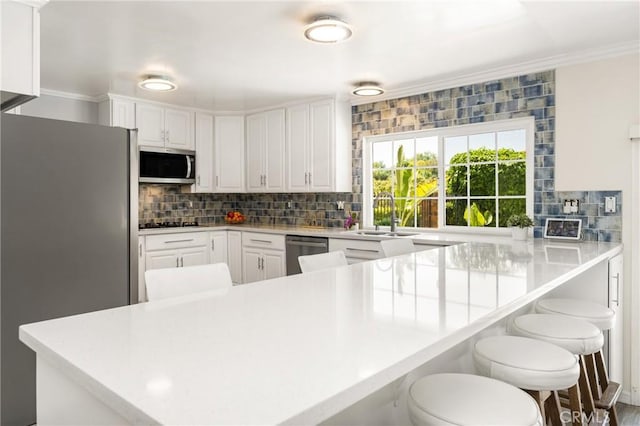 15541 Olive Branch Dr, La Mirada, CA 90638 - kitchen with appliances with stainless steel finishes, a sink, backsplash, white cabinetry, and a peninsula