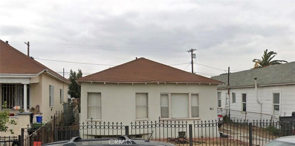 911 E 55th St, Los Angeles, CA 90011 - view of side of property featuring stucco siding, a fenced front yard, and a shingled roof
