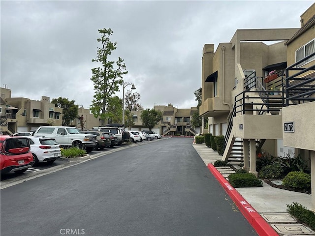 view of asphalt street featuring a residential view, stairway, and street lighting