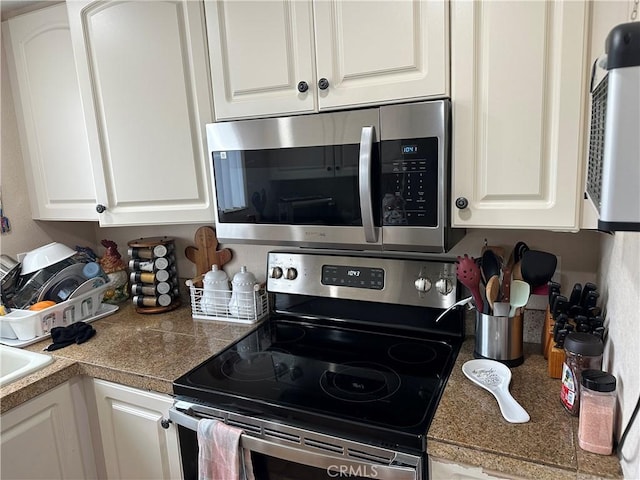 kitchen with stainless steel appliances, tile countertops, and white cabinetry
