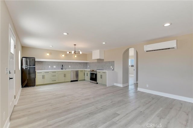 1809 Delgada Ave, Landers, CA 92285 - kitchen with stainless steel appliances, an AC wall unit, light countertops, decorative backsplash, and arched walkways