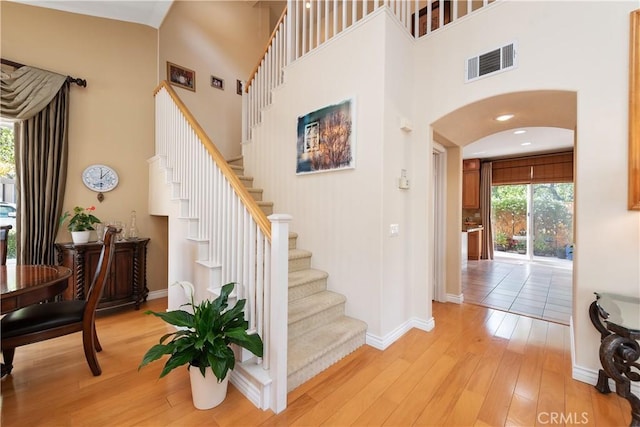 11803 Sortino Ct, Moorpark, CA 93021 - foyer entrance featuring a high ceiling, arched walkways, light wood-style floors, baseboards, and stairs
